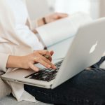 kobieta siedzaca i sprawdzajaca informacje na laptopie